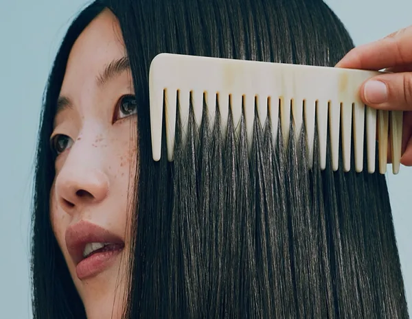 A model combing long, glossy dark hair: Goldwell Dualsenses